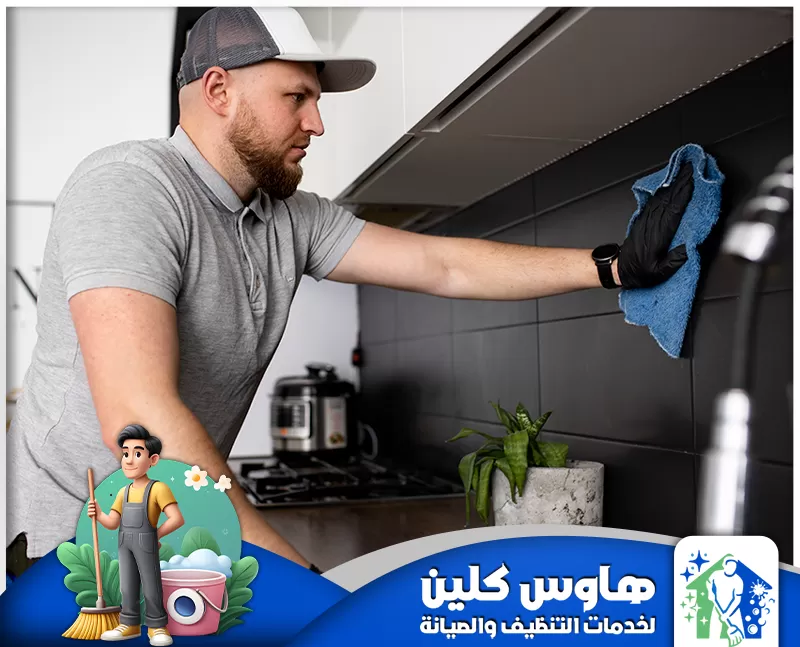 شركة تنظيف مطابخ بالدمام | 0506747660 | هاوس كلين رجل يرتدي بذلة عمل وقفازات ينظف مطبخا بدقة، مُسلطا الضوء على خدمات التنظيف الاحترافية في الدمام.